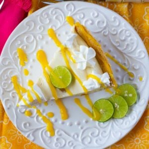 Overhead image of a slice of KMango Key Lime Pie garnished with mango sauce, whipped cream and lime slices.