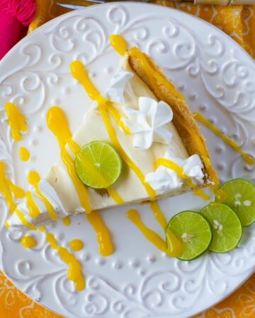 Overhead image of a slice of KMango Key Lime Pie garnished with mango sauce, whipped cream and lime slices.