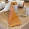 Homemade peach fruit leather roll ups on a wooden cutting board.