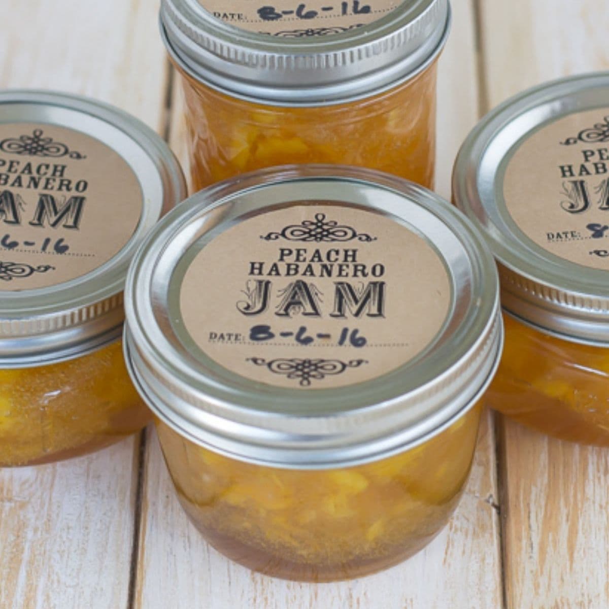 Canning jars filled with peach habanero jam on a table.