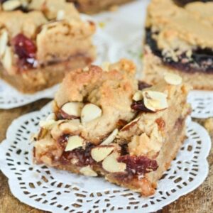 Peanut butter and jelly filled dessert bars on a wooden cutting board.