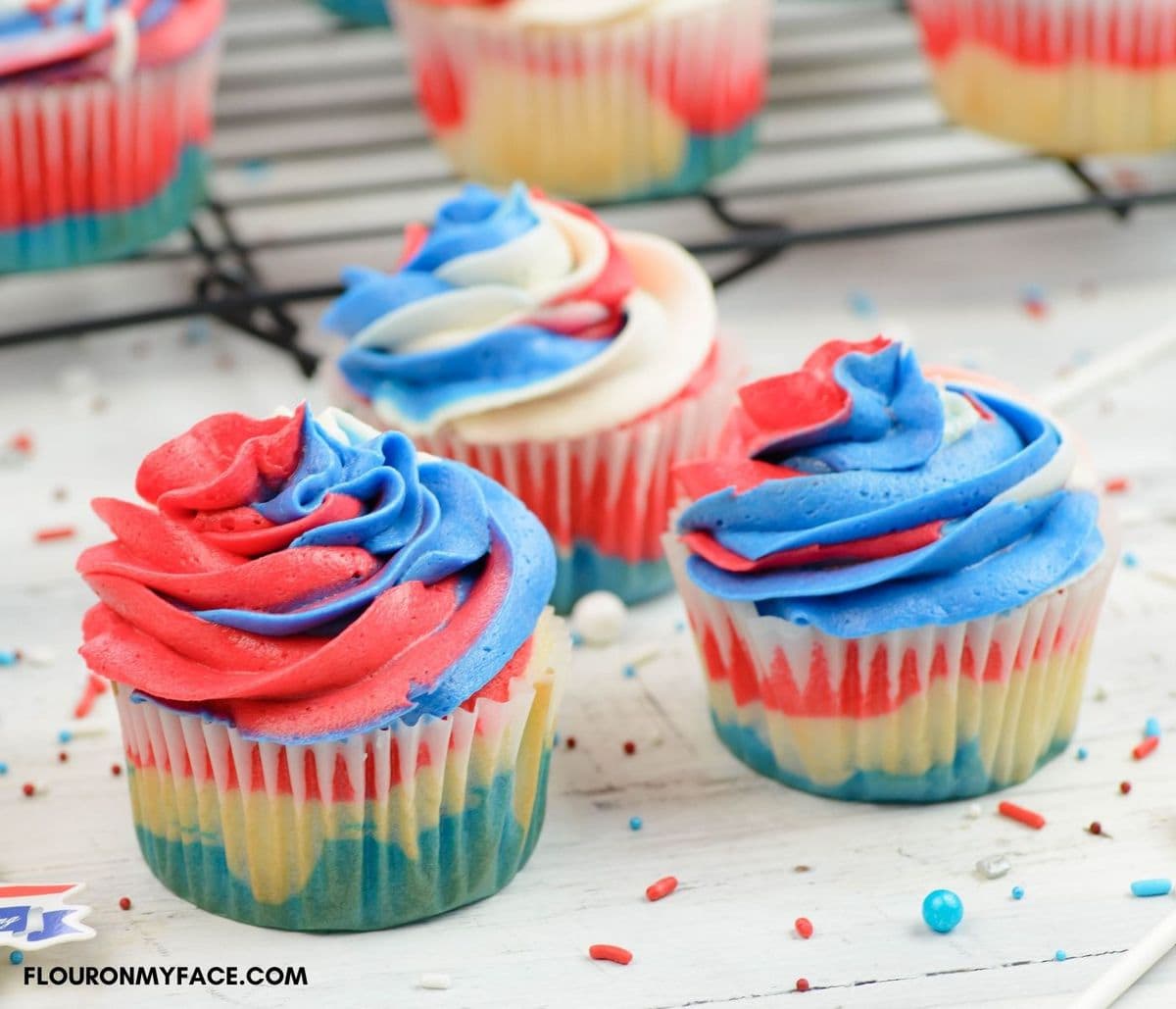 Three 4th of july cupcakes decorated with red, white and blue frosting.