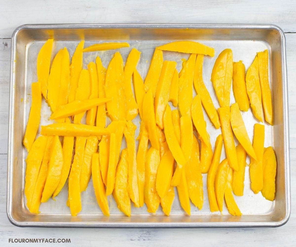 Slice mango on an aluminum tray.
