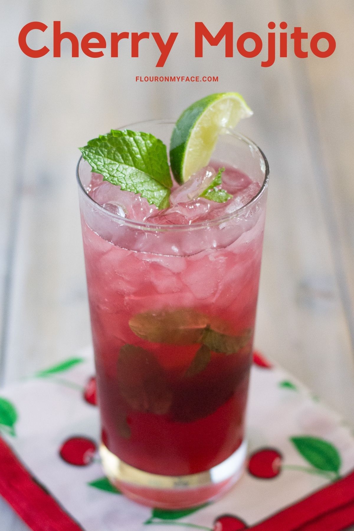 A tall glass on a cloth napkin filled with a sweet cherry mojito.