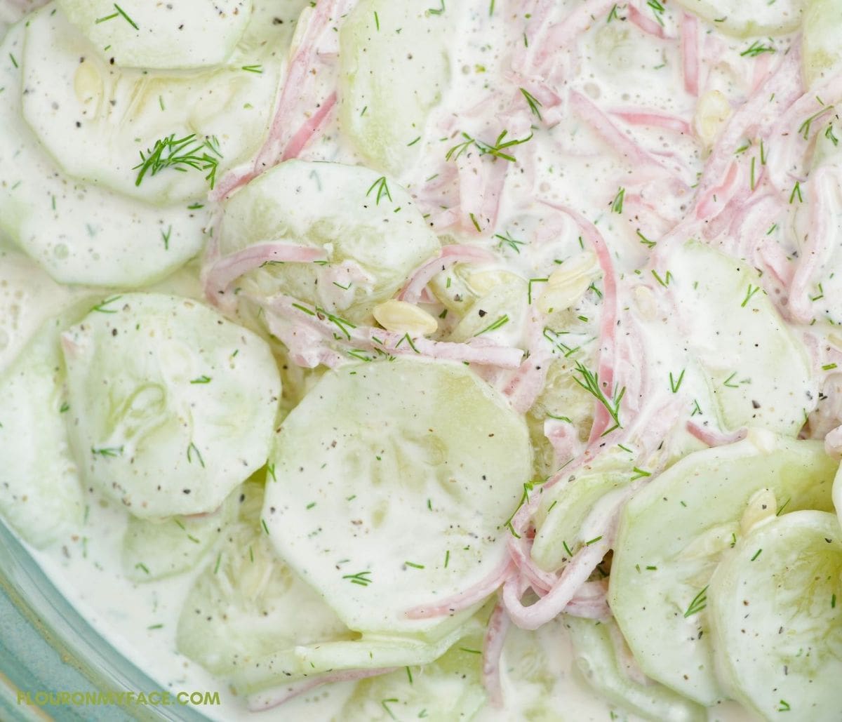 Closeup image of cucumber and onion salad in a serving bowl.