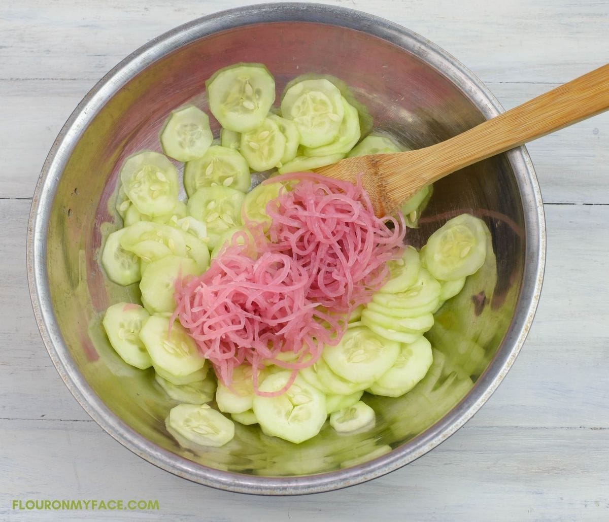 A bowl of sliced cucumbers and pickled red onions.
