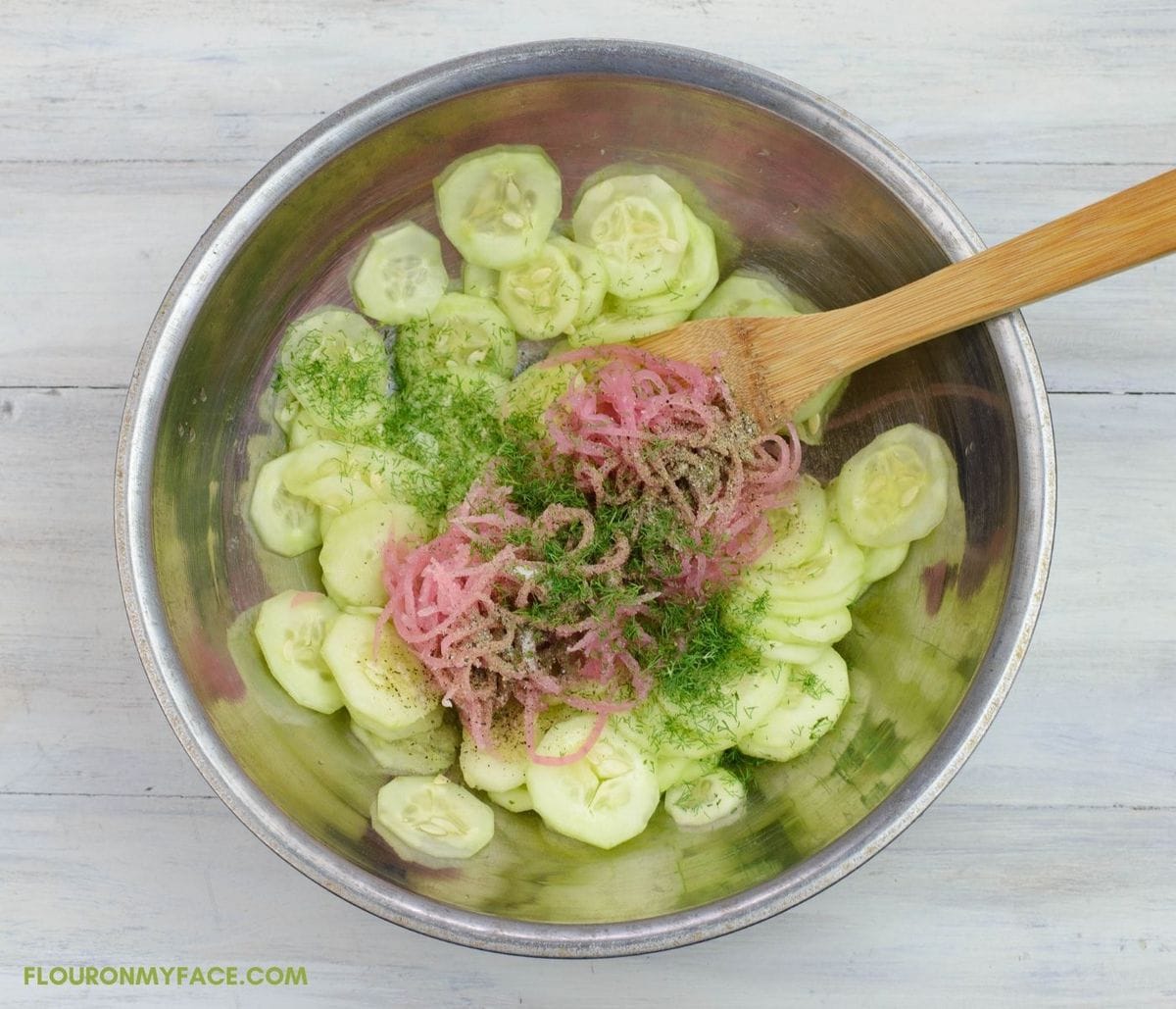 Combining Cucumber Salad ingredients in a mixing bowl.