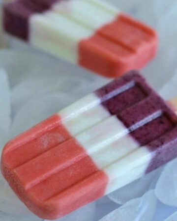 Red, white and blueberry ice pops on a bed of ice.