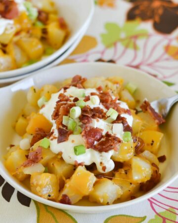 Small serving bowl filled with a Cheese Bacon Garlic Potato Side dish.
