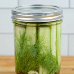 A wide mouth pint jar filled with refrigerator dill pickle spears.