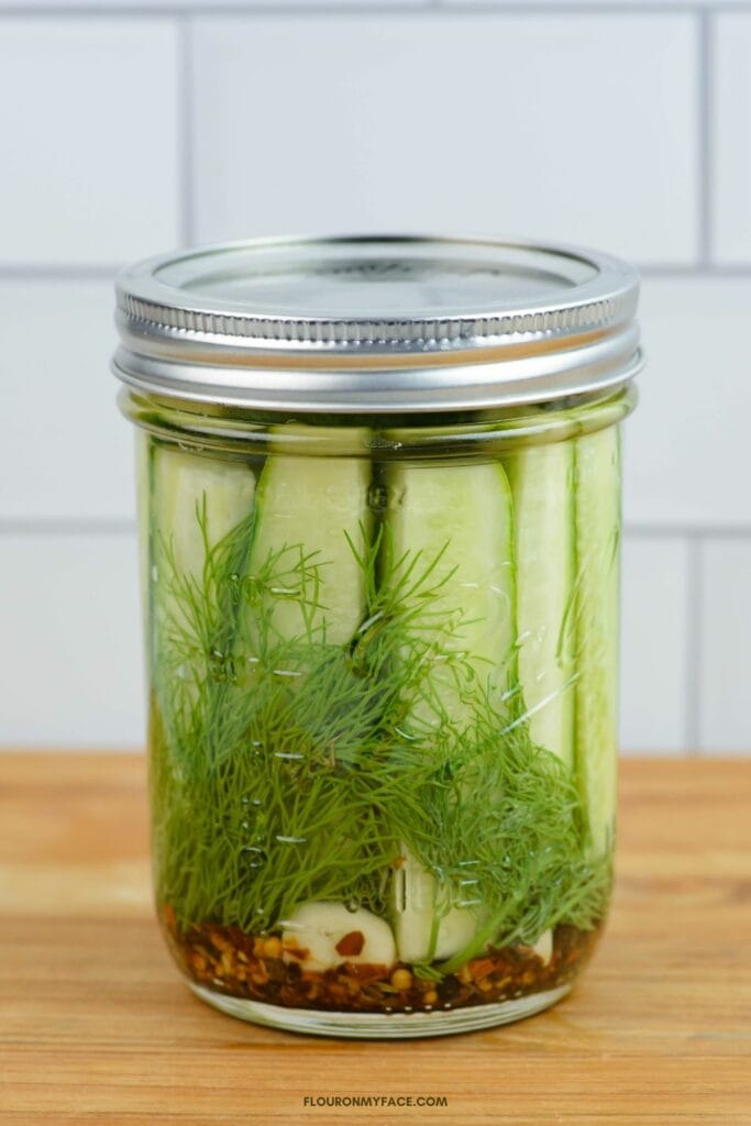 A wide mouth pint jar filled with refrigerator dill pickle spears.