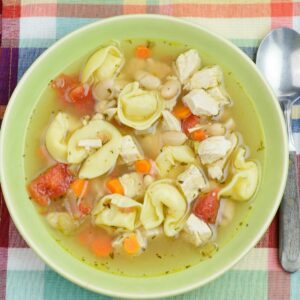 A green bowl filled with chicken tortellini white bean soup.