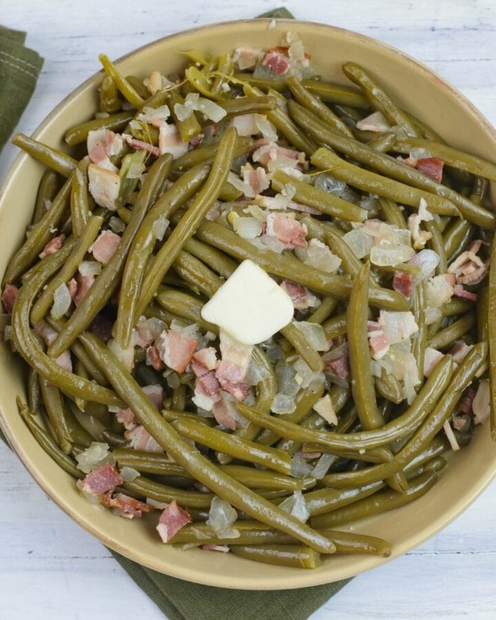 A large serving bowl filled with crock pot green beans with bacon.