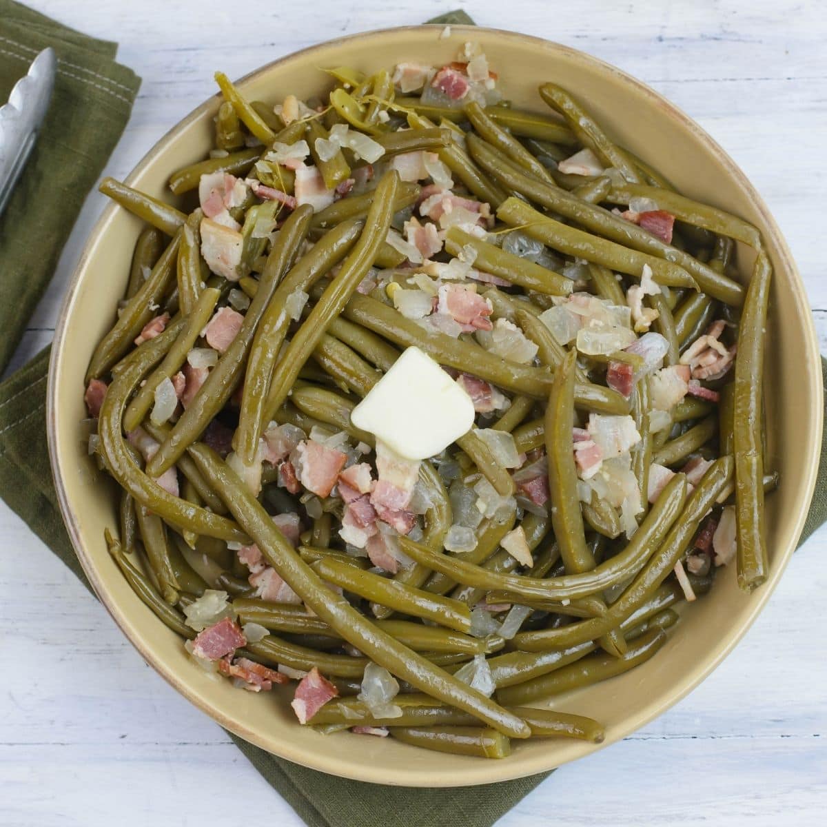 A large serving bowl filled with crock pot green beans with bacon.