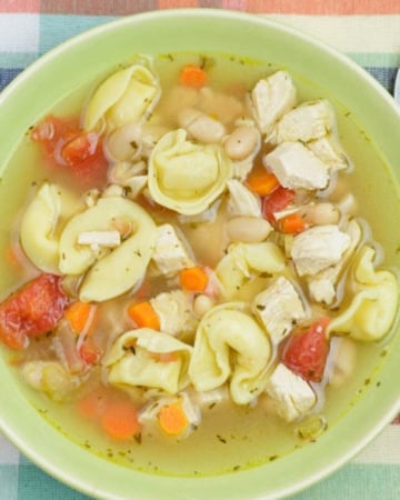 A green bowl filled with chicken tortellini white bean soup.