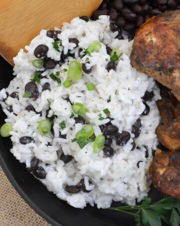 A serving of creamy coconut rice garnished with green onion and black beans.