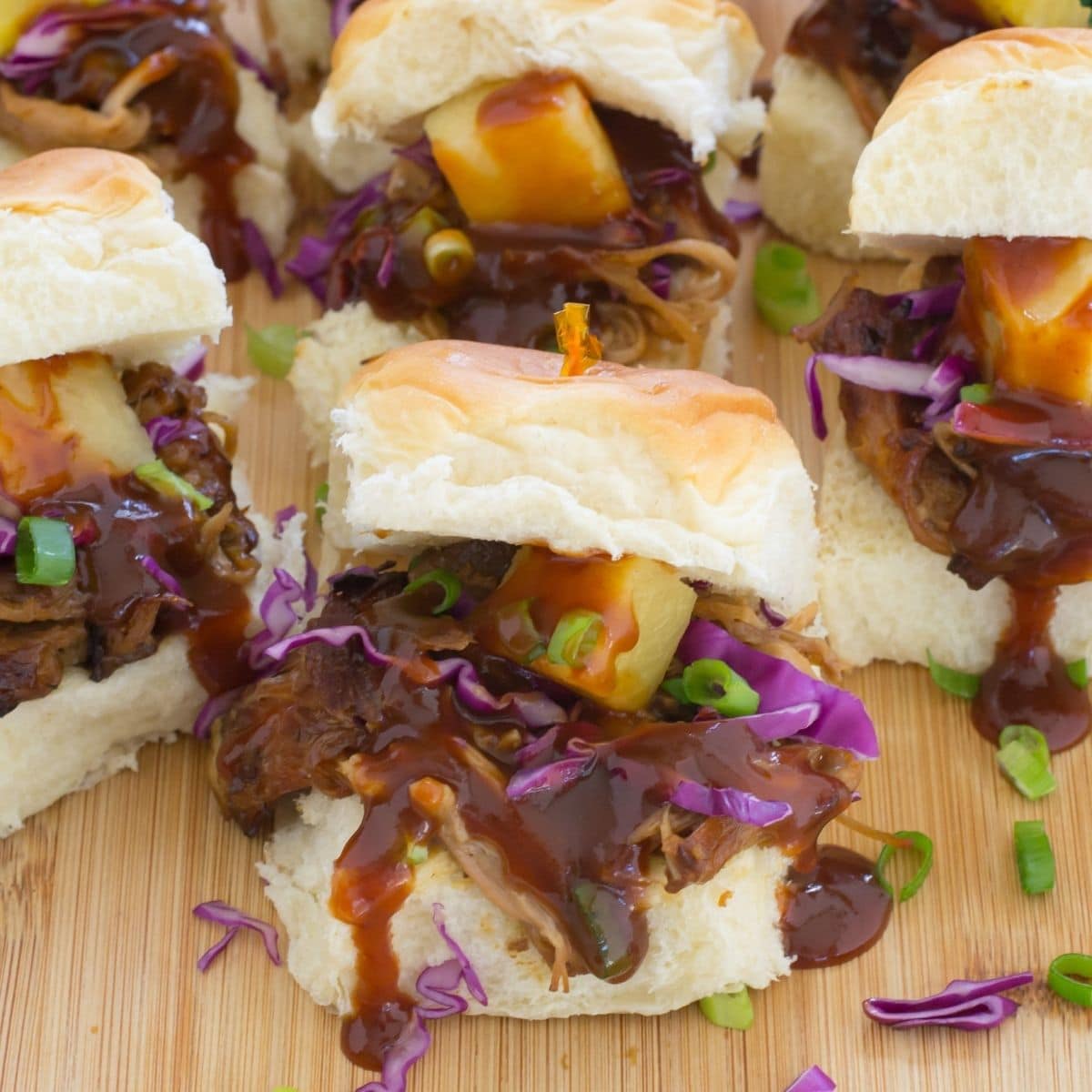 Crock Pot Pineapple Pulled Pork Sliders on a wooden cutting board.