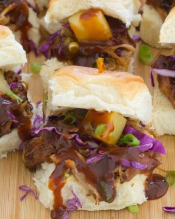 Crock Pot Pineapple Pulled Pork Sliders on a wooden cutting board.