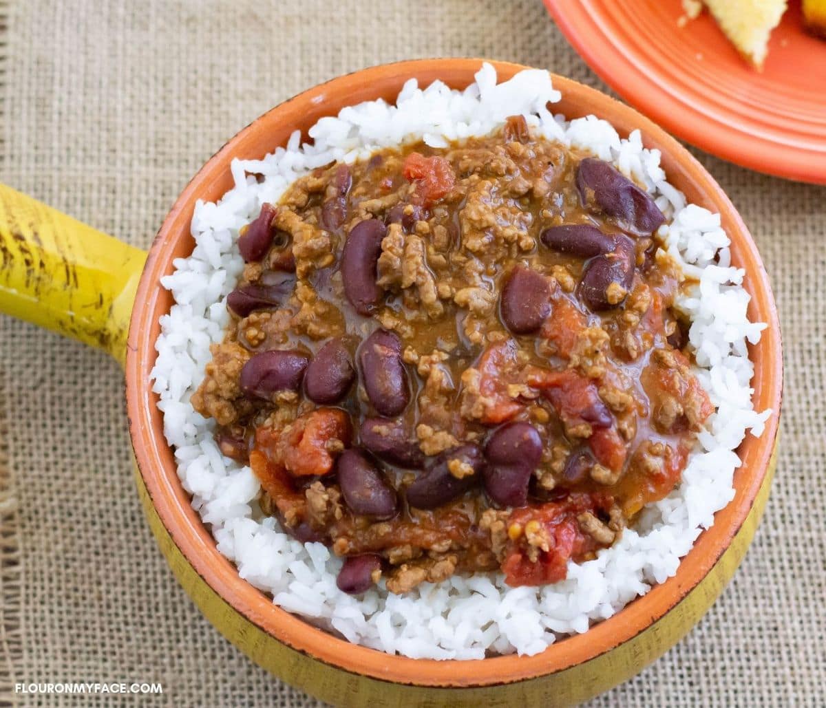 a crock style bowl filled with chili over white rice.