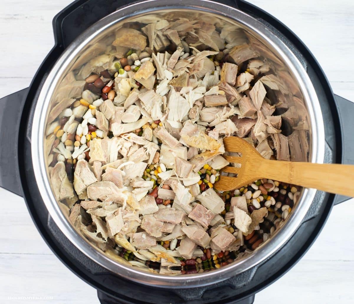 Overhead image of cubed turkey and dried beans mixed in the pot.