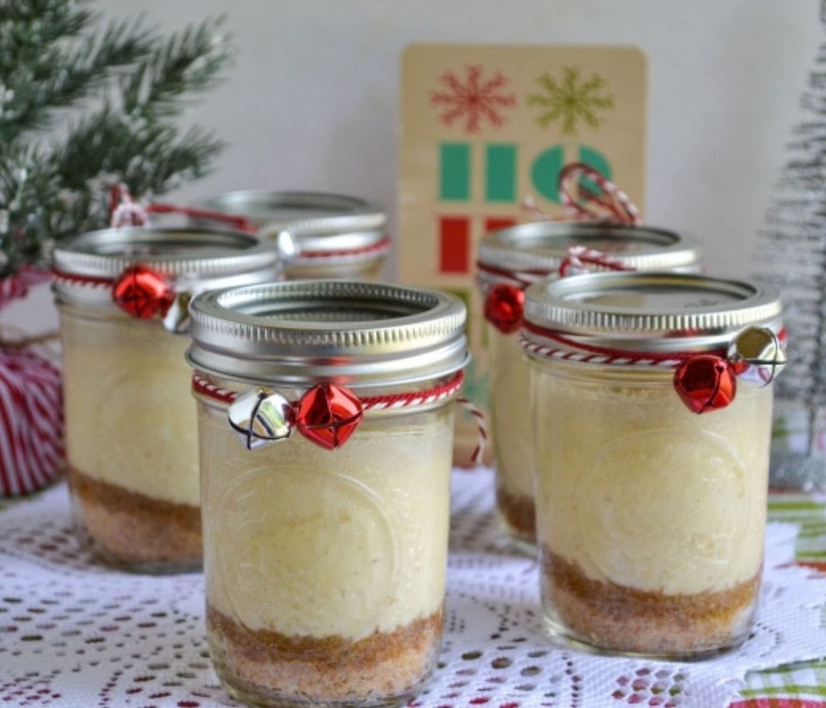 Eggnog Cheesecake in a mason jar decorated with red bells and twine.