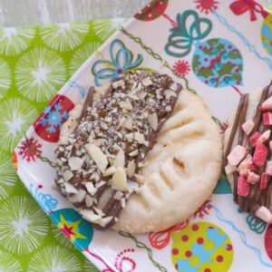 Chocolate dippe Christmas shortbread cookies on a holiday plate.