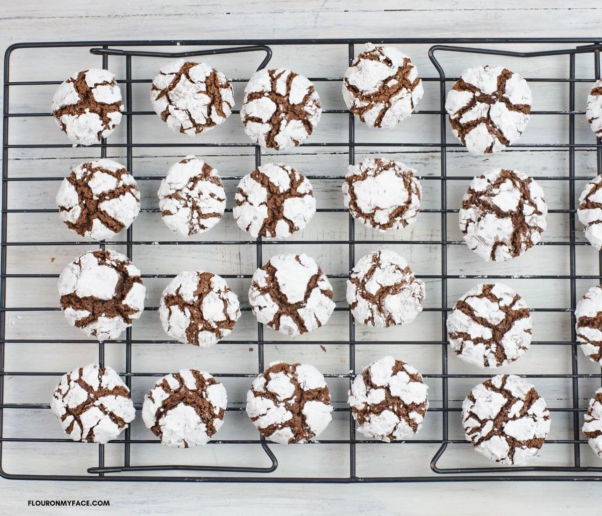 Cooling chocolate crinkle cookies on a black wire cooling rack.