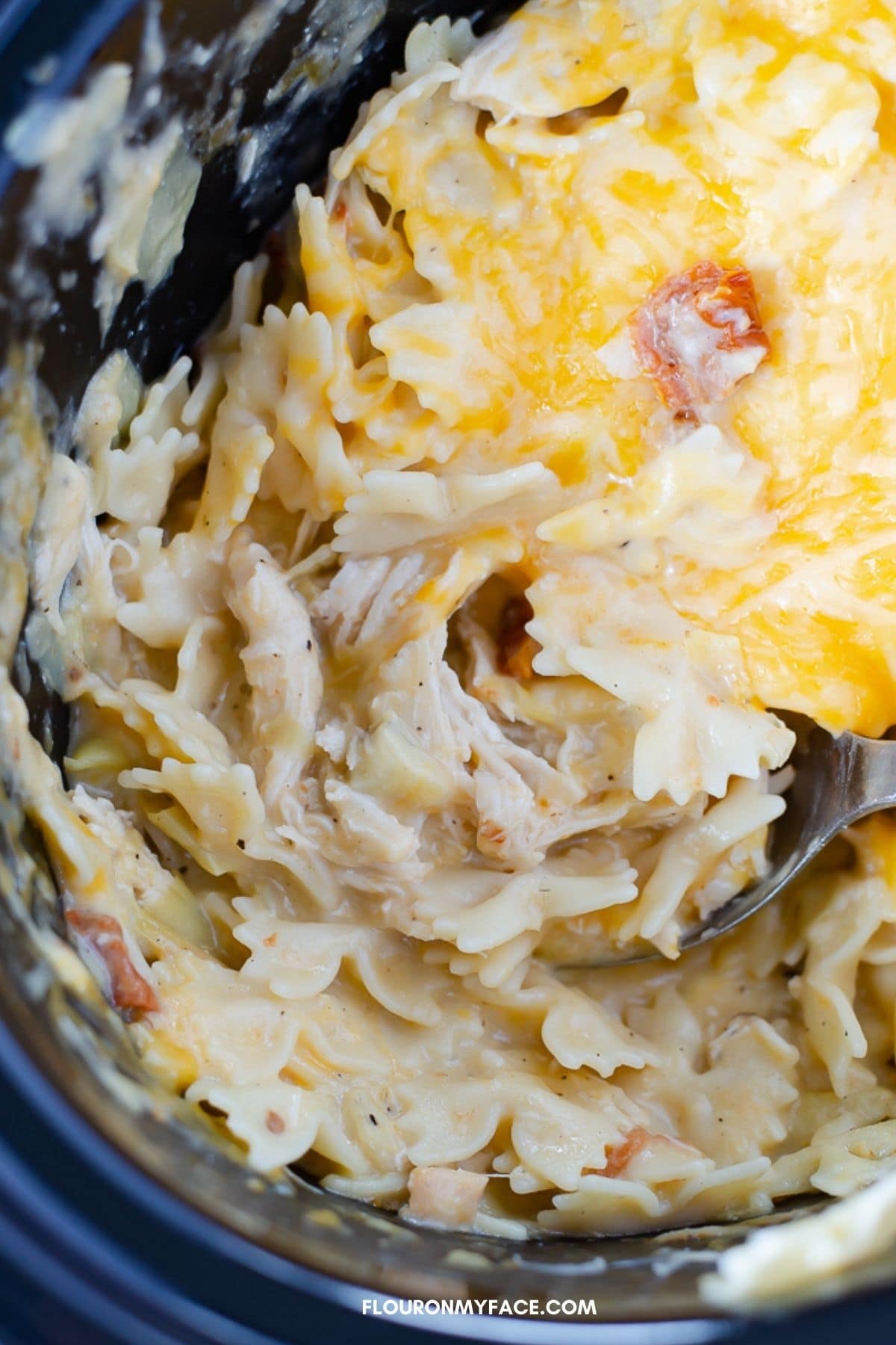 Overhead view of crock pot casserole with melted cheese on top.