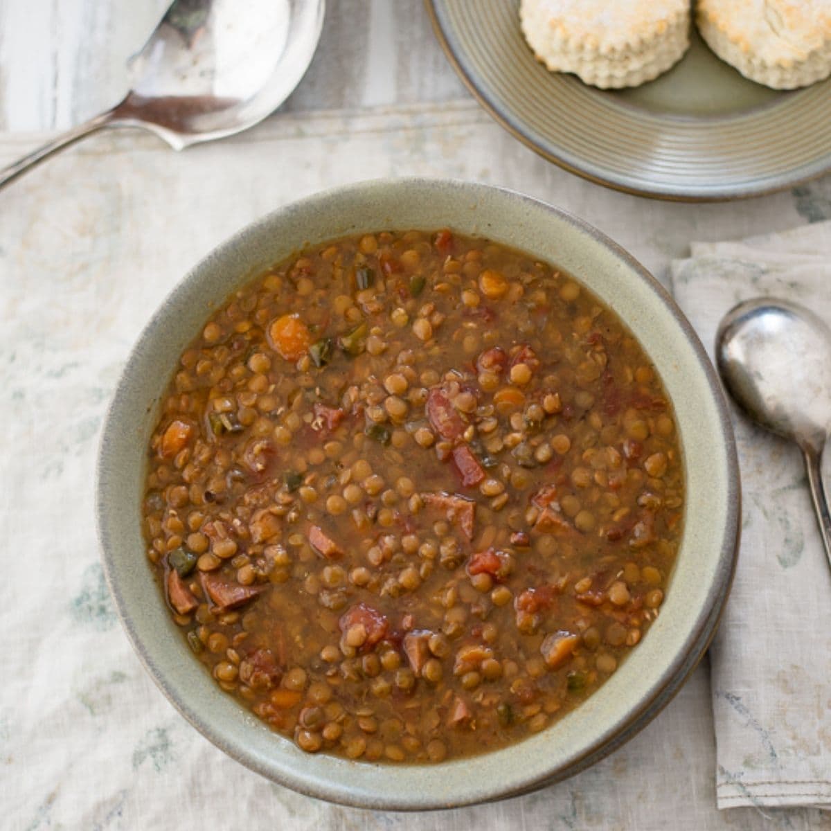 Lentil and ham soup in a bowl with biscuits.