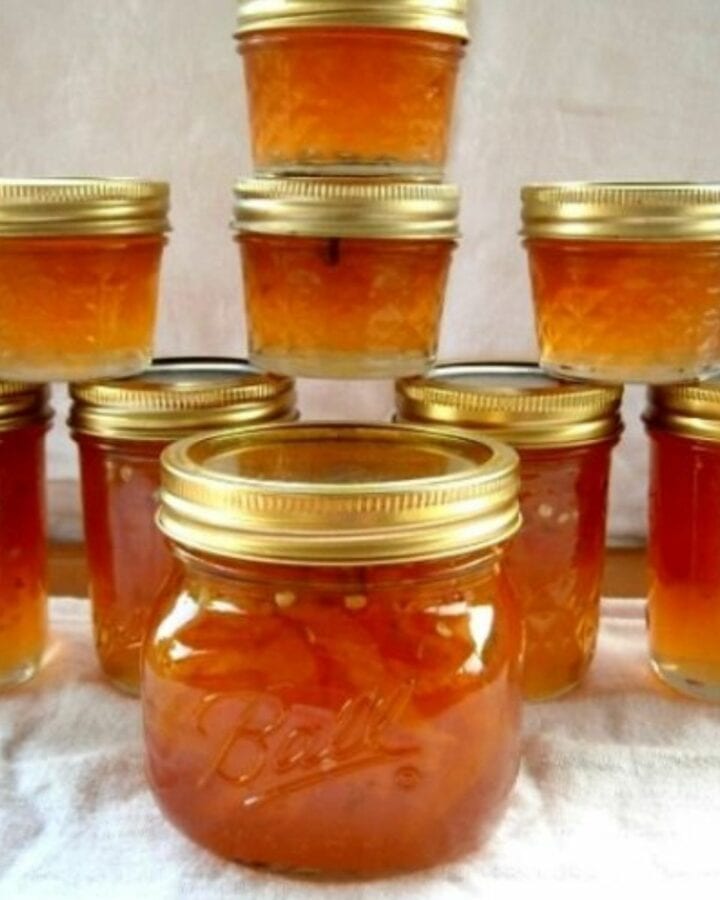 A stack of canning jars filled with sweet and spicy peach jalapeno jam.