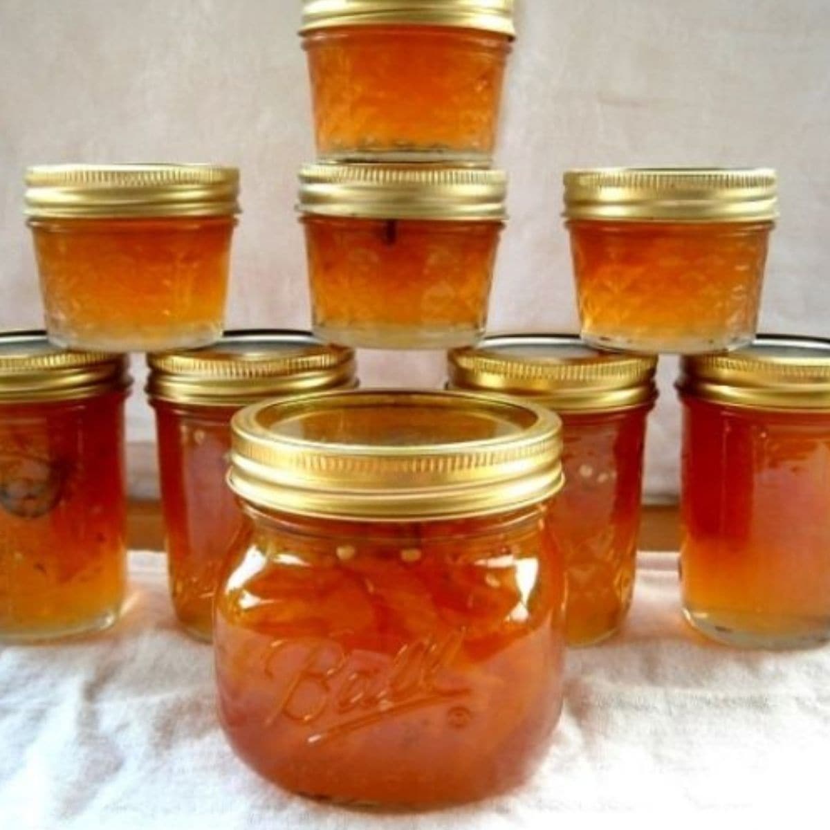 A stack of canning jars filled with sweet and spicy peach jalapeno jam.