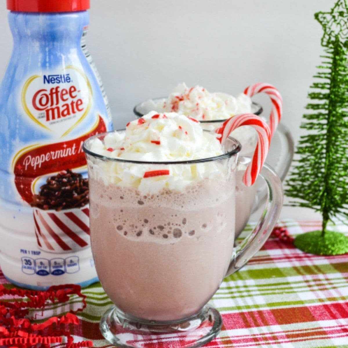 A clear mug filled with peppermint mocha frozen hot chocolate topped with whipped cream.