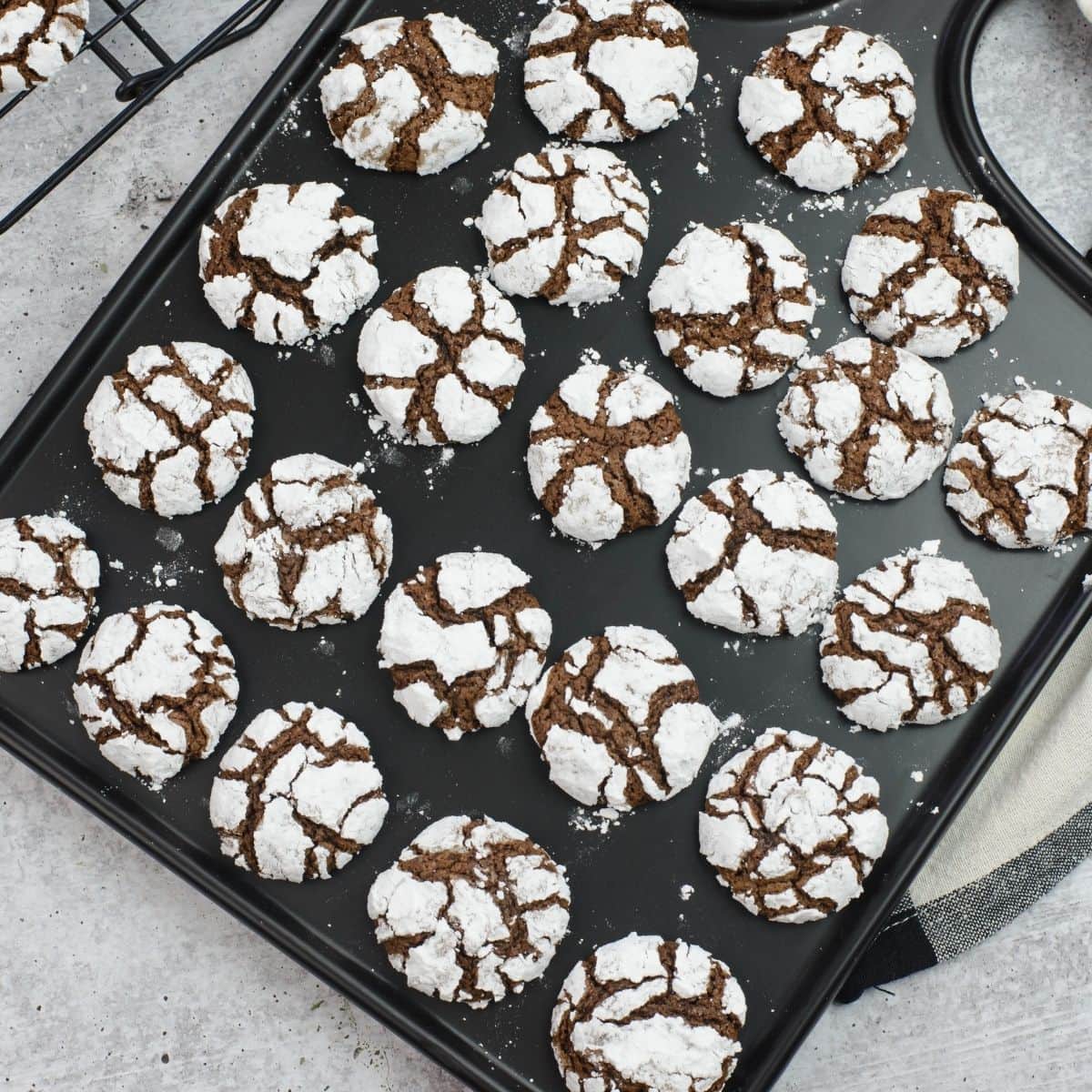 Serving chocolate crinkle cookies on a black glass serving tray.