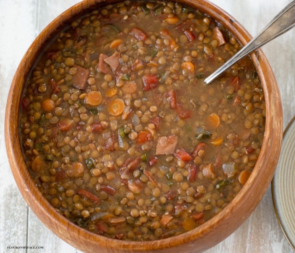 Slow cooker Lentils soup recipe served in a wooden bowl with fresh baked homemade biscuits.
