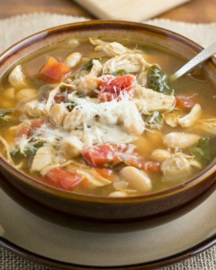 A brown soup bowl filled with tuscan chicken and bean soup.