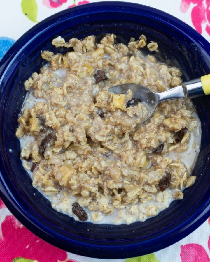 A blue bowl filled with a serving of homemade apple cinnamon raisin oatmeal.