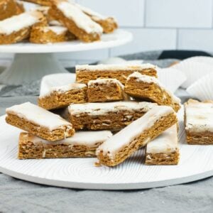 German Honey Bars (Lebkuchen) stacked on a dessert plate with a cake stand in the background with more.