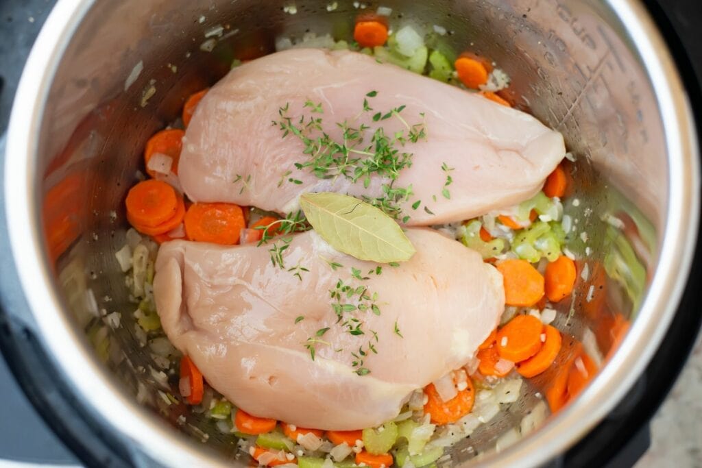Adding boneless chicken and fresh thyme and bay leaf to the pot.