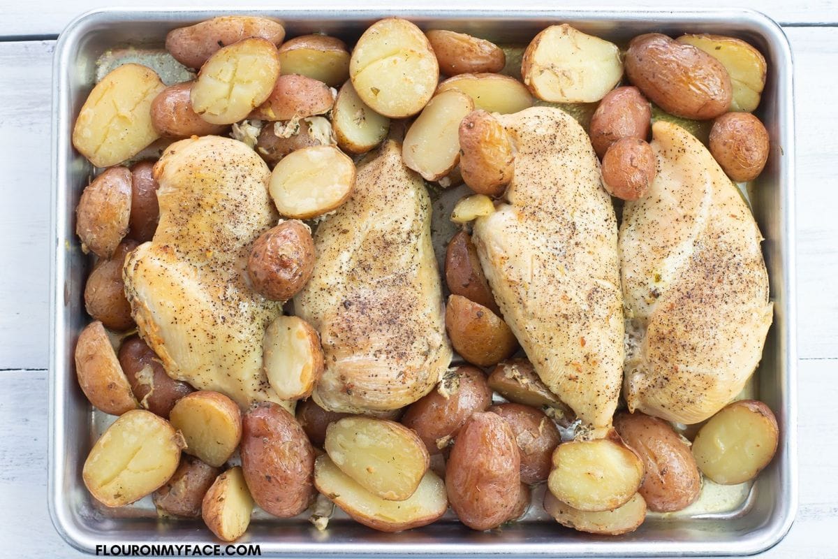 4 boneless chicken breasts and tender baby potatoes on a baking tray.