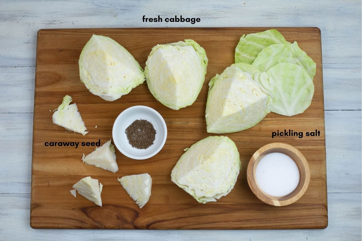 Homemade sauerkraut ingredients on a wooden cutting board.