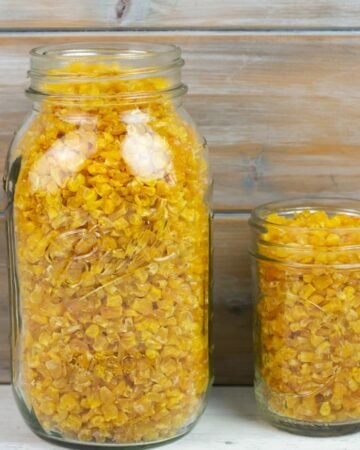 Two glass mason jars filled with dehydrated corn made with frozen corn kernels bought at the grocery store.