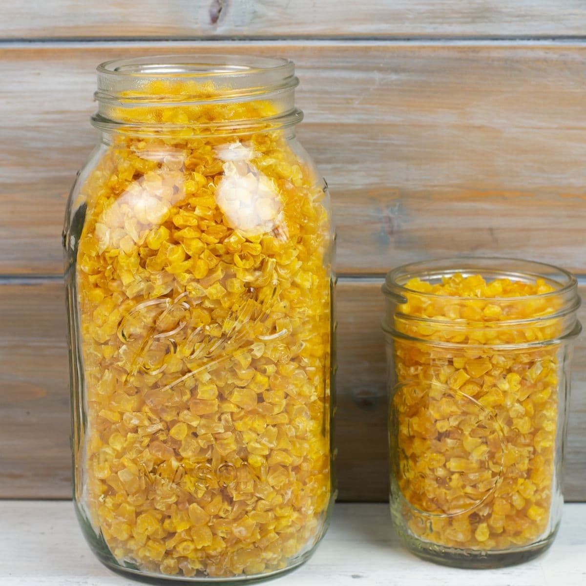 Two glass mason jars filled with dehydrated corn made with frozen corn kernels bought at the grocery store.