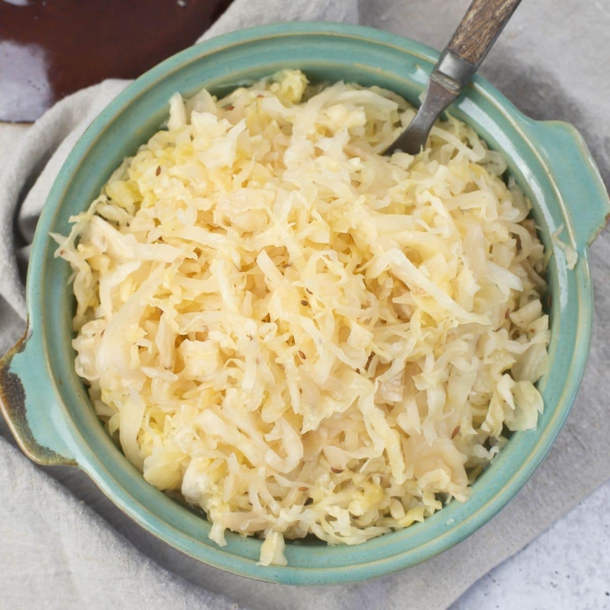 Overhead image of a teal bowl filled with homemade sauerkraut.