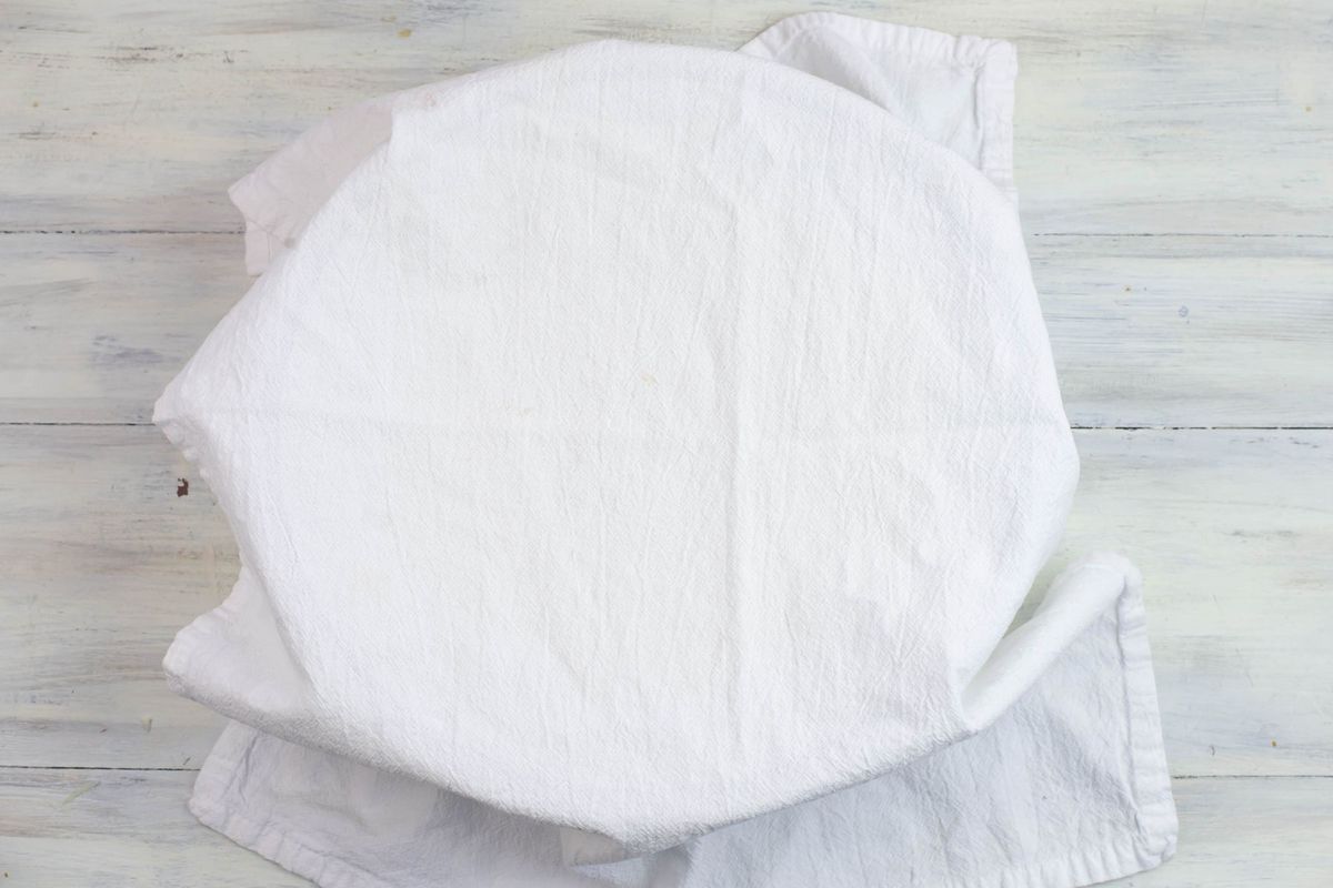 A glass bowl covered with a white towel.