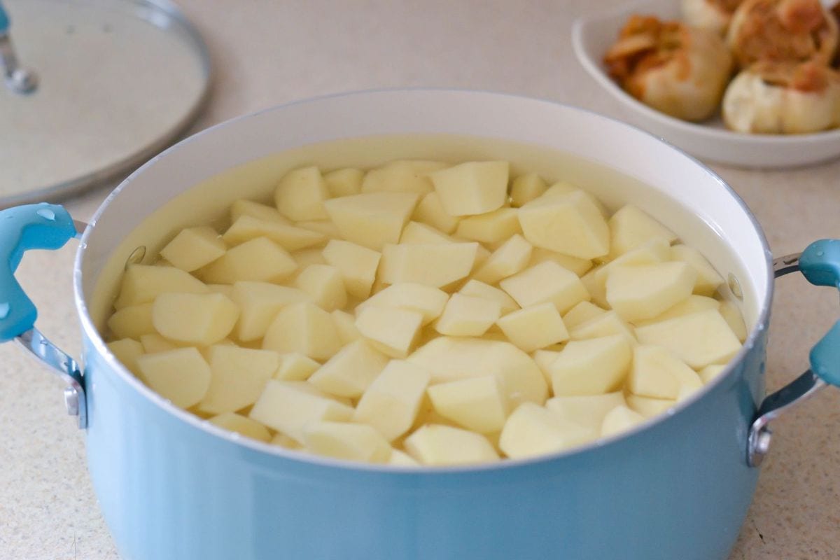 A 5 quart pot filled with quartered potatoes soaking in water.