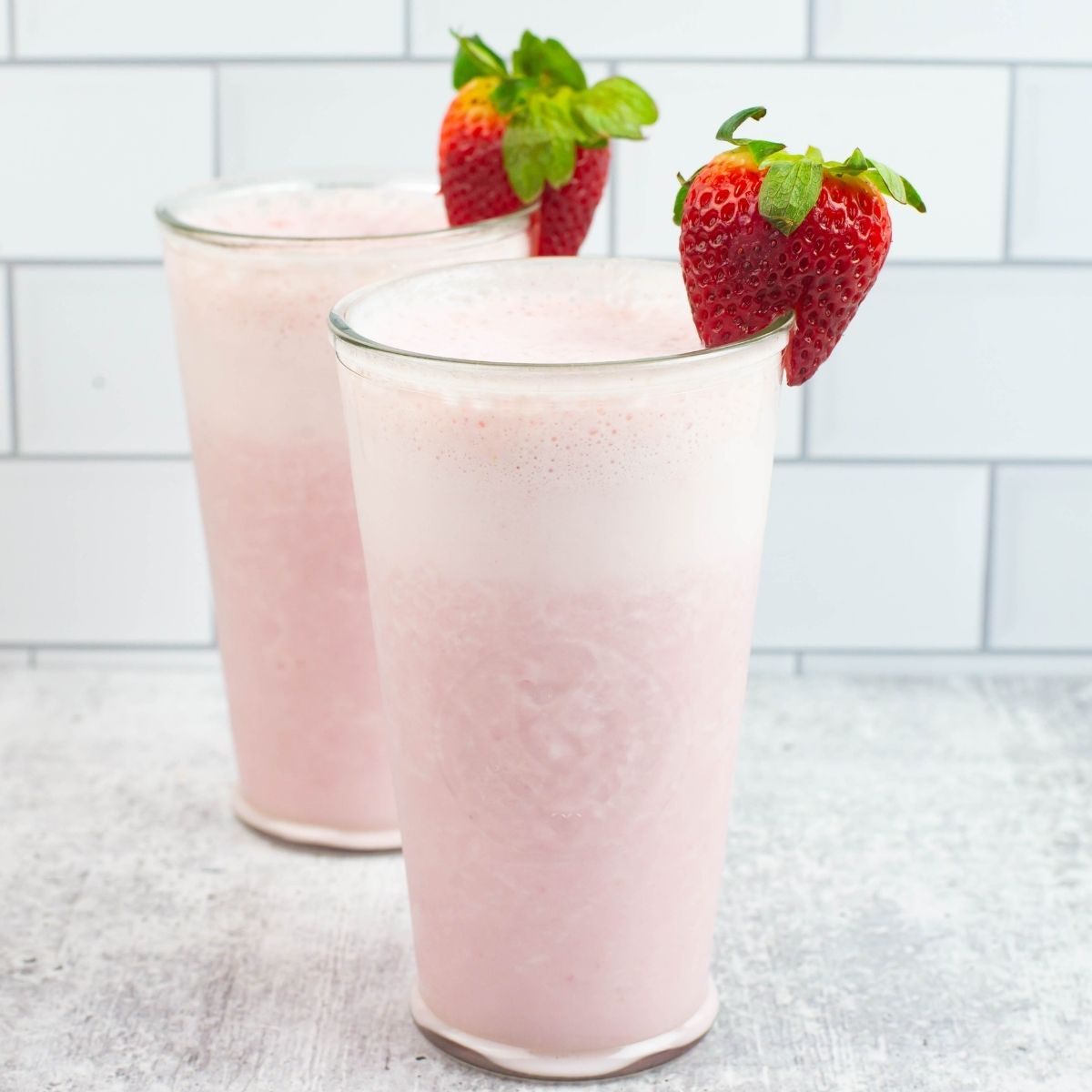 Two tall glasses filled with a homemade Tropical Smoothie made with coconut milk and fruit.