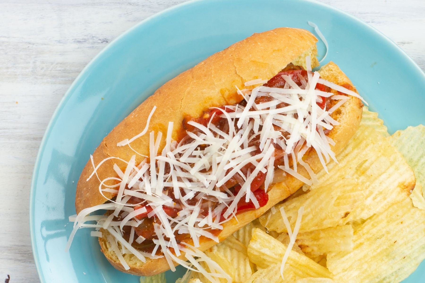 overhead photo of Instant Pot Sausage and Peppers Sandwiches served on a hoagie roll with shredded cheese.