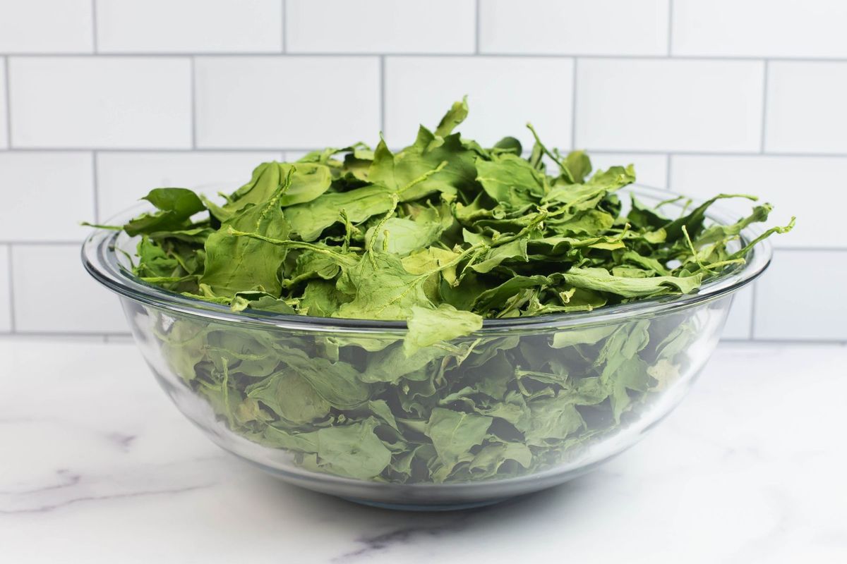 A large bowl overflowing with dried spinach leaves.