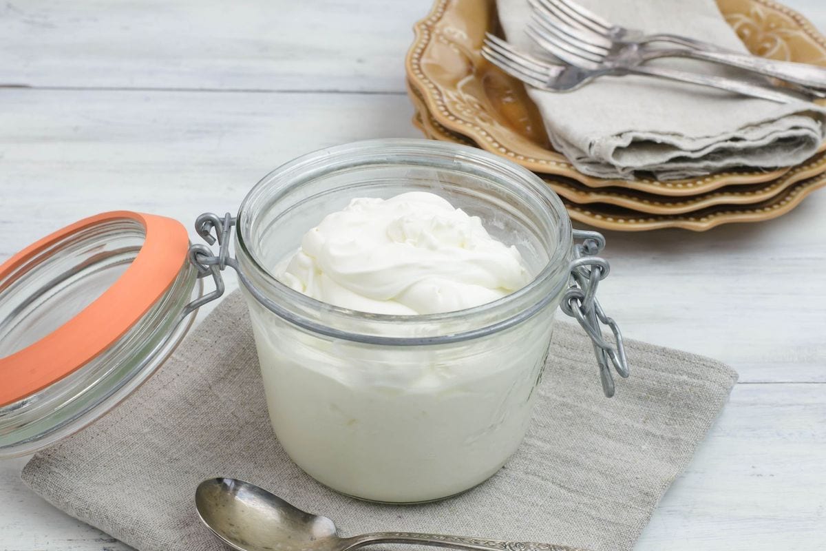 A low round jar filled with homemade sour cream.