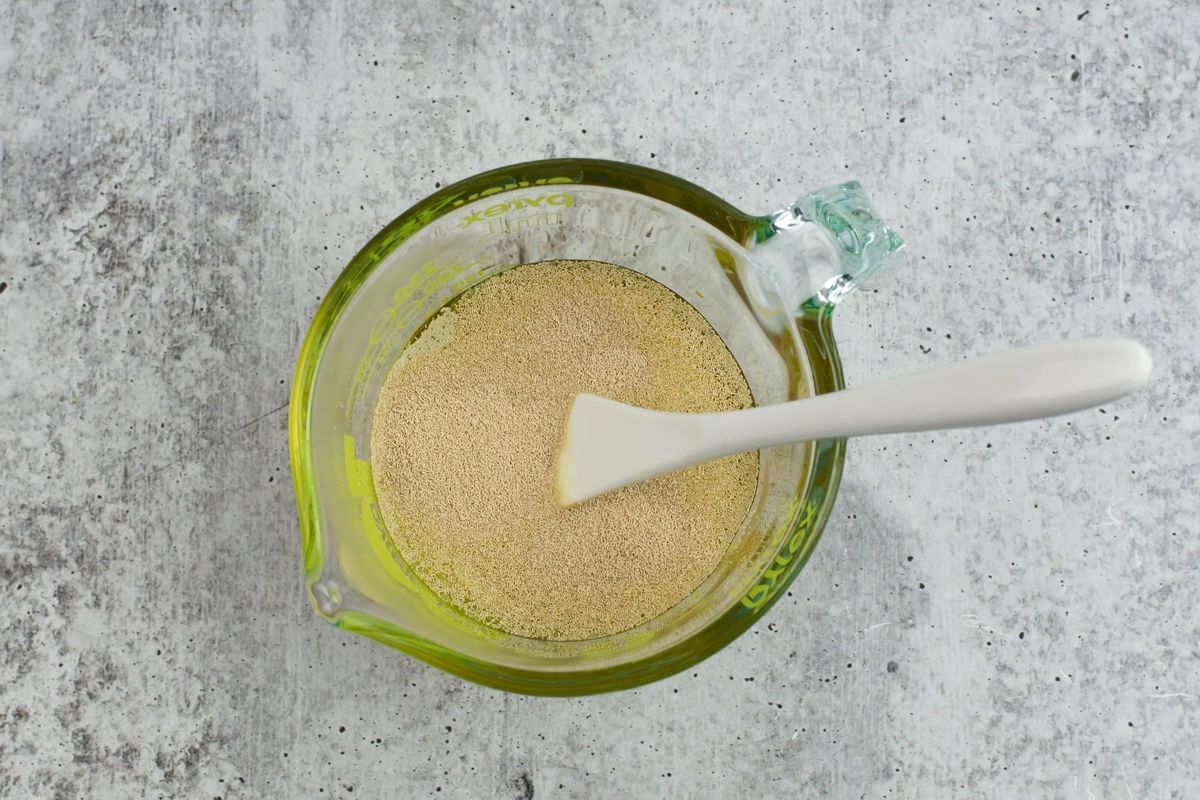 Mixing yeast, oil, honey and water in a glass measuring cup.